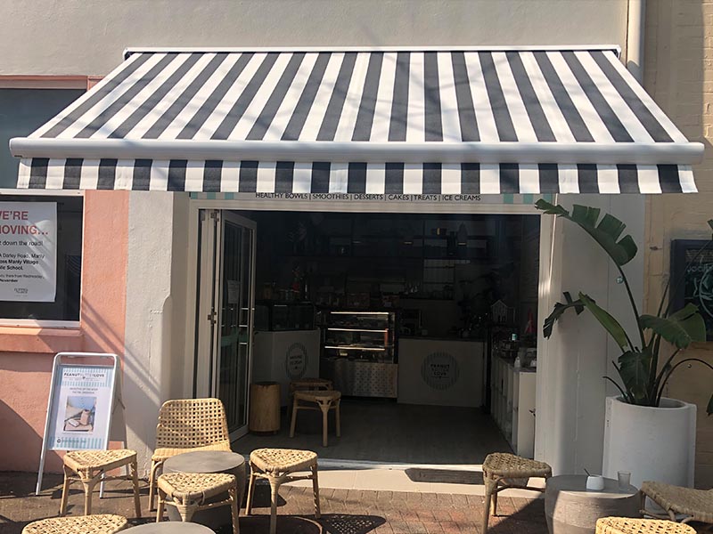 retractable folding arm awning with black and white striped fabric