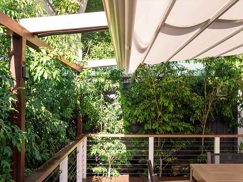 retractable awning over timber pergola frame gives sun, wind and rain protection