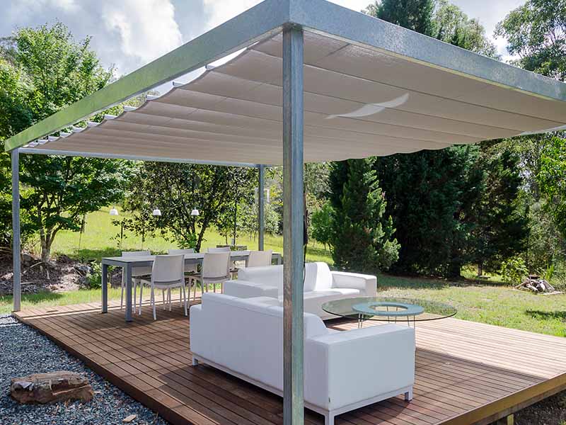 Free standing outdoor cabana with retractable shade sail