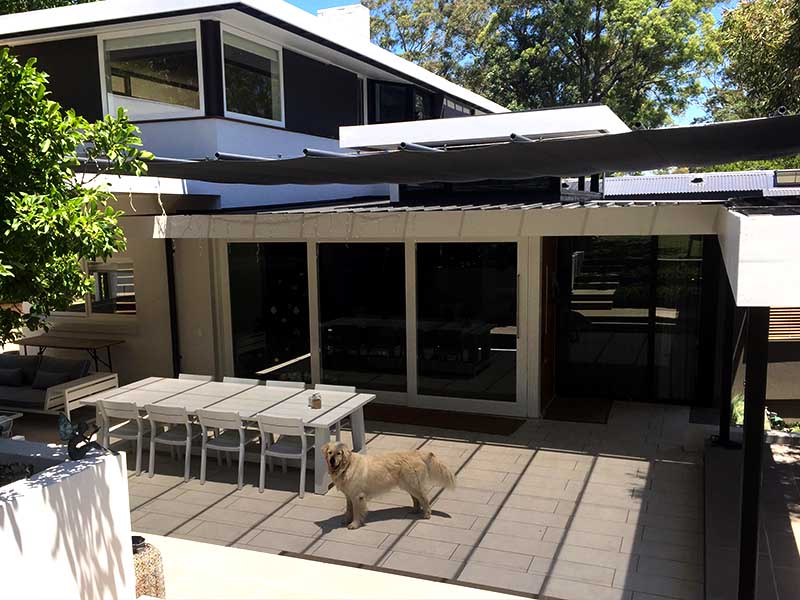 Retractable shade sail over courtyard