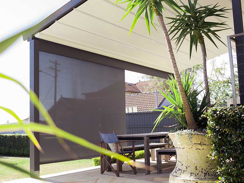 Retractable straight drop awning used as a screen in outdoor living area