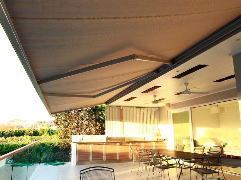 Extended folding arm awning with heaters over outdoor area